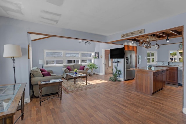 living room featuring beamed ceiling, baseboards, and wood finished floors