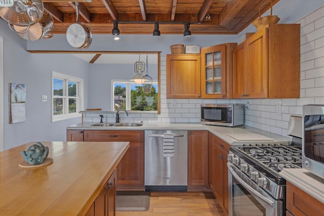 kitchen with stainless steel appliances, brown cabinetry, wooden ceiling, and a sink