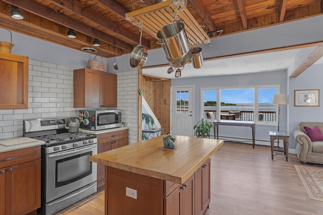 kitchen with a baseboard heating unit, appliances with stainless steel finishes, beam ceiling, decorative backsplash, and light wood finished floors