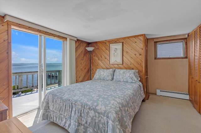 bedroom featuring a baseboard radiator, a water view, light carpet, wood walls, and access to outside