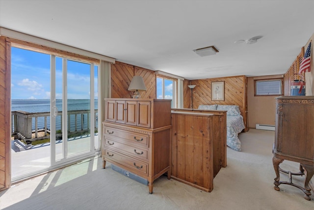 bedroom with a water view, a baseboard heating unit, light carpet, wood walls, and access to outside