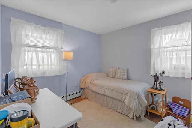 bedroom featuring a baseboard heating unit and multiple windows