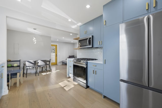 kitchen with light wood-style flooring, blue cabinets, stainless steel appliances, light countertops, and backsplash