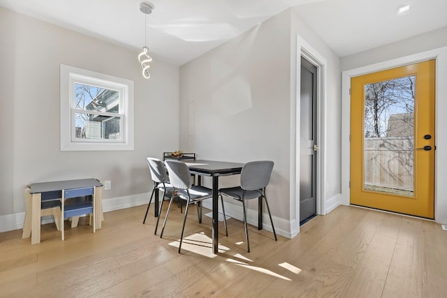 dining area with baseboards, light wood-style flooring, and a healthy amount of sunlight