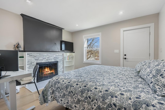 bedroom featuring a stone fireplace and wood finished floors