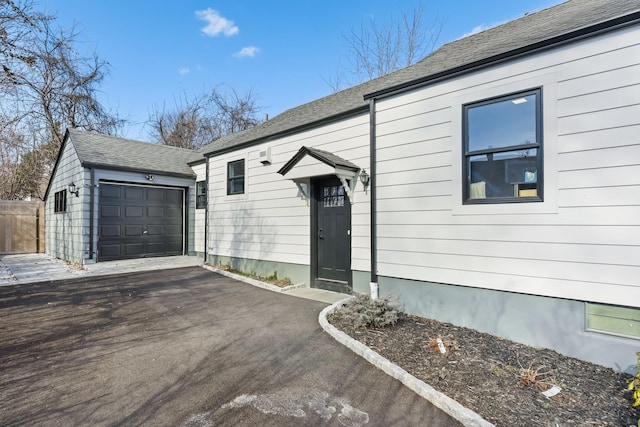 view of front of property featuring roof with shingles, aphalt driveway, and an outbuilding