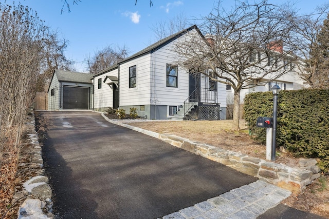 view of front of home with aphalt driveway, an outdoor structure, and an attached garage