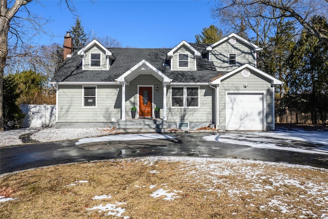 new england style home with a garage, a shingled roof, a chimney, and aphalt driveway