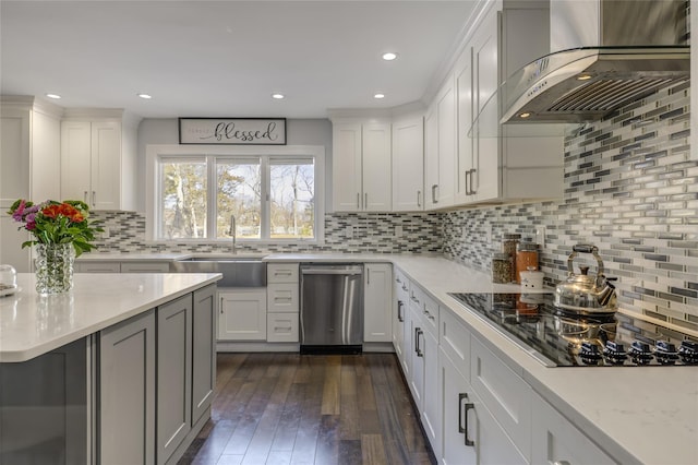 kitchen with dark wood finished floors, a sink, wall chimney range hood, dishwasher, and black electric cooktop