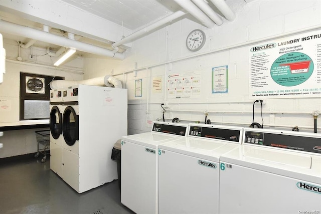 common laundry area with washer and dryer and concrete block wall