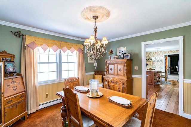 dining room with a baseboard heating unit, ornamental molding, a wainscoted wall, and a notable chandelier