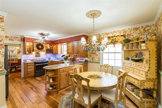 dining room featuring wallpapered walls, a wealth of natural light, a notable chandelier, and wainscoting