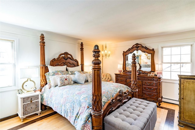 bedroom featuring a baseboard heating unit and light wood-type flooring