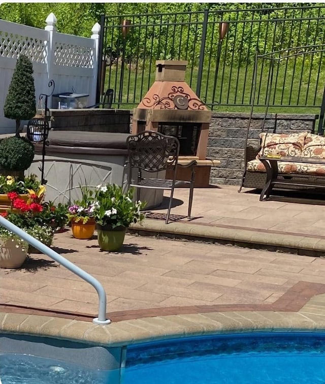 pool with fence, exterior fireplace, and a patio