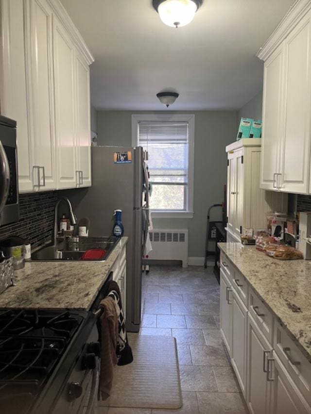 kitchen with white cabinets, radiator heating unit, backsplash, and a sink