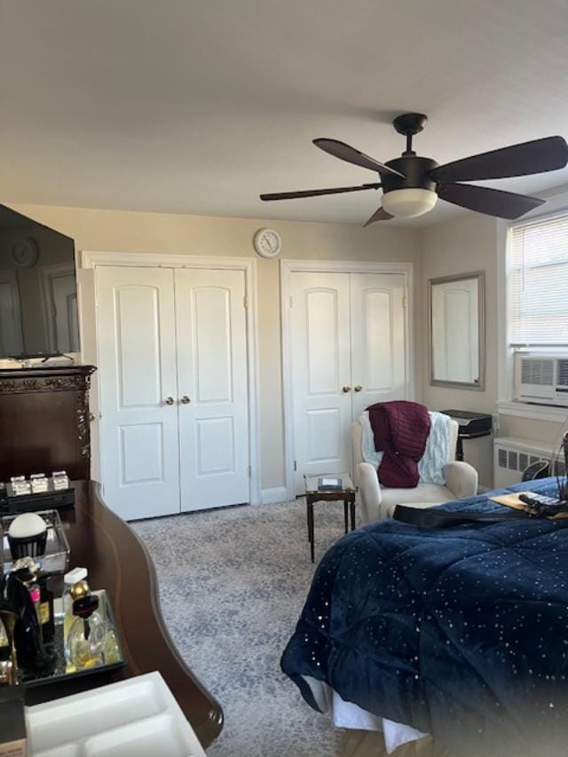 bedroom featuring baseboards, radiator heating unit, ceiling fan, cooling unit, and multiple closets