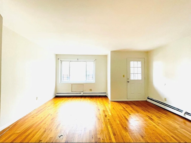 unfurnished room with plenty of natural light, baseboard heating, wood-type flooring, and a baseboard radiator