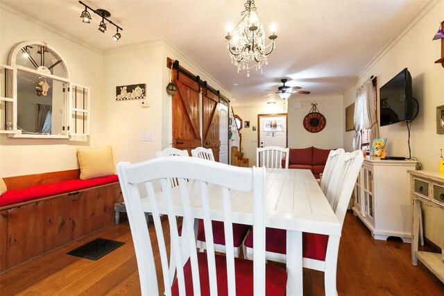 dining space with a barn door, ceiling fan with notable chandelier, wood finished floors, visible vents, and crown molding