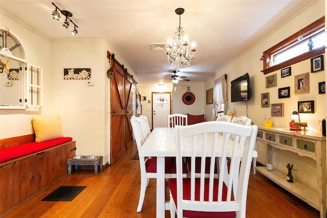 dining space with a barn door, visible vents, and ornamental molding