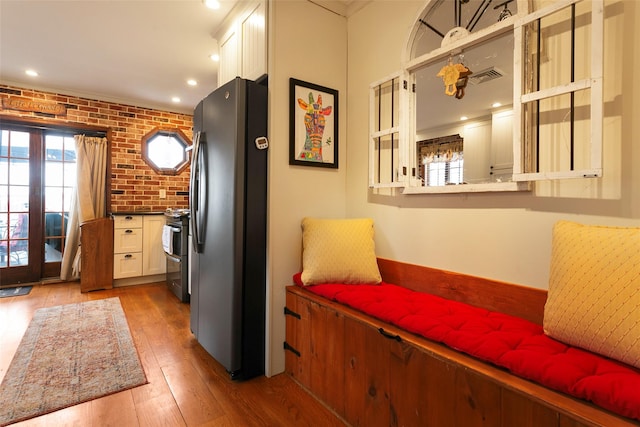 interior space with visible vents, brick wall, wood-type flooring, appliances with stainless steel finishes, and recessed lighting