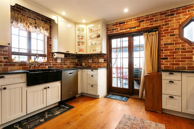 kitchen featuring a sink, brick wall, light wood-type flooring, and dishwasher