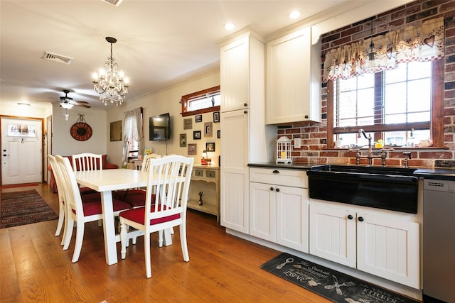 kitchen with visible vents, dishwashing machine, crown molding, light wood-type flooring, and a sink