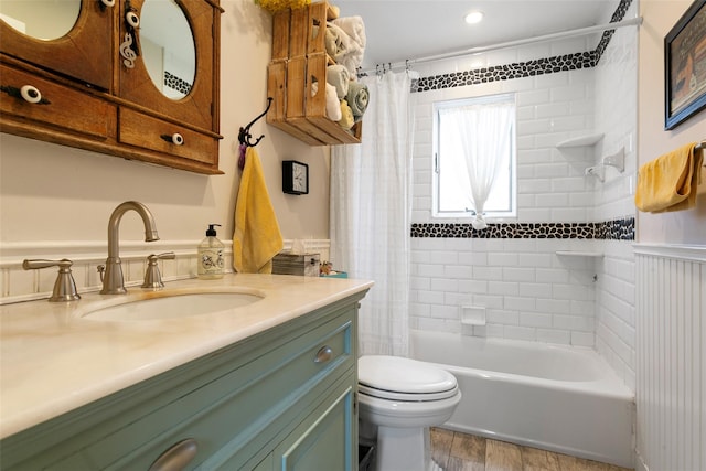 full bathroom featuring toilet, a wainscoted wall, shower / tub combo, wood finished floors, and vanity