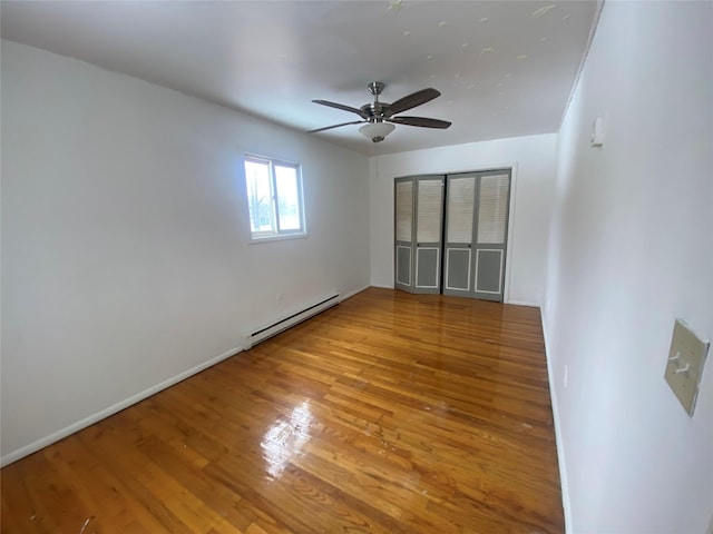 empty room with a baseboard heating unit, light wood-style flooring, a ceiling fan, and baseboards