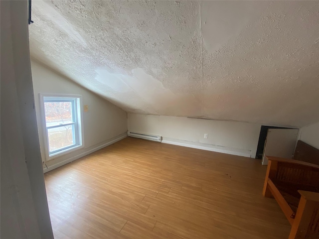 bonus room featuring a baseboard radiator, vaulted ceiling, light wood-style flooring, and a textured ceiling