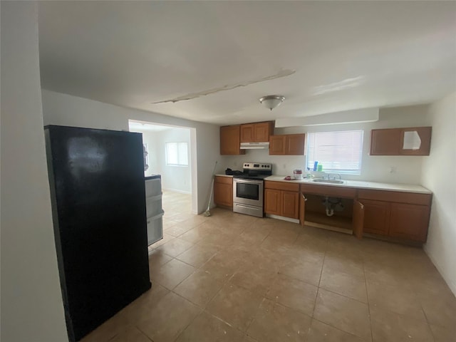 kitchen with electric range, light countertops, a healthy amount of sunlight, under cabinet range hood, and a sink