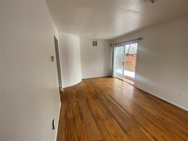 unfurnished room with hardwood / wood-style flooring, visible vents, and baseboards