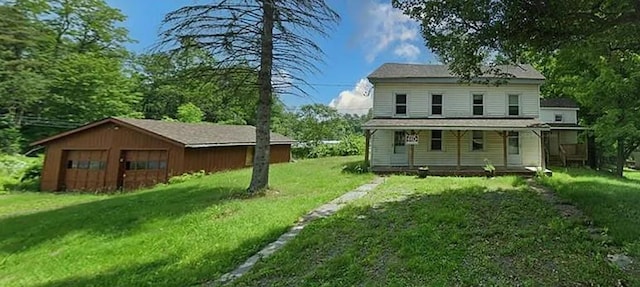 rear view of property with an outbuilding, covered porch, and a yard