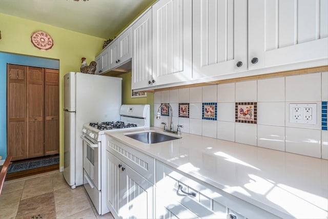 kitchen featuring light tile patterned floors, light countertops, white gas stove, white cabinetry, and a sink