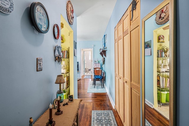 hallway with dark wood finished floors and baseboards