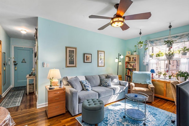 living area with dark wood-type flooring, baseboards, and a ceiling fan