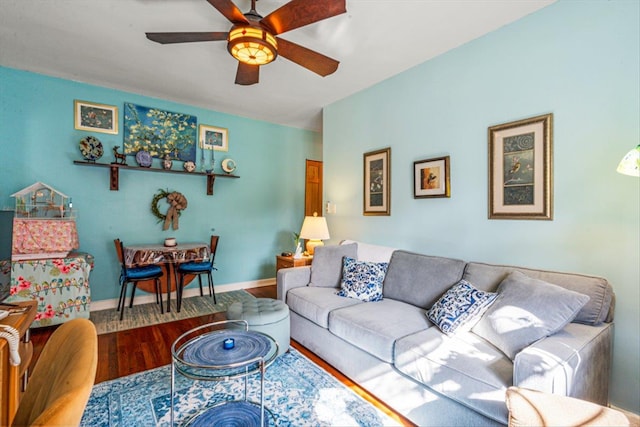 living room with ceiling fan, baseboards, and wood finished floors