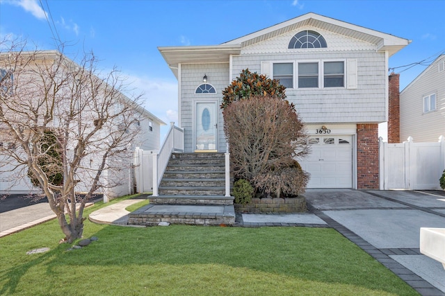 view of front of house featuring a front lawn, driveway, fence, a garage, and brick siding