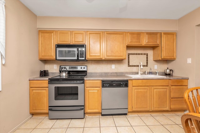 kitchen featuring a sink, decorative backsplash, light tile patterned floors, and stainless steel appliances