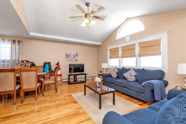 living room featuring a wealth of natural light, light wood-type flooring, a ceiling fan, and vaulted ceiling