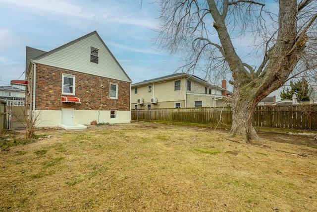 back of house featuring a yard, brick siding, and a fenced backyard