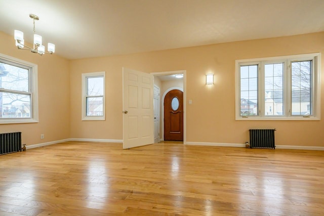 foyer featuring a notable chandelier, radiator heating unit, baseboards, and light wood-style floors