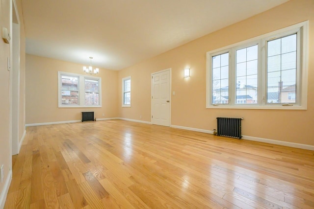 unfurnished living room with light wood finished floors, an inviting chandelier, and radiator