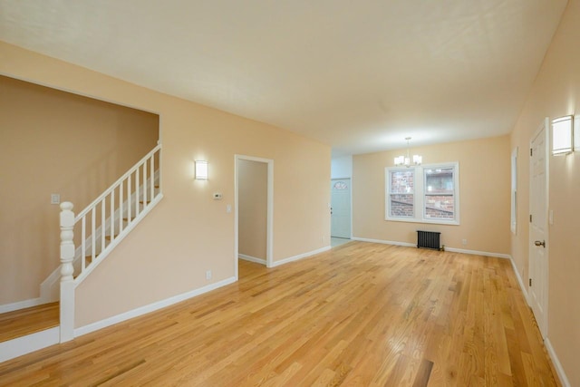 unfurnished living room with a notable chandelier, baseboards, stairway, light wood-type flooring, and radiator heating unit