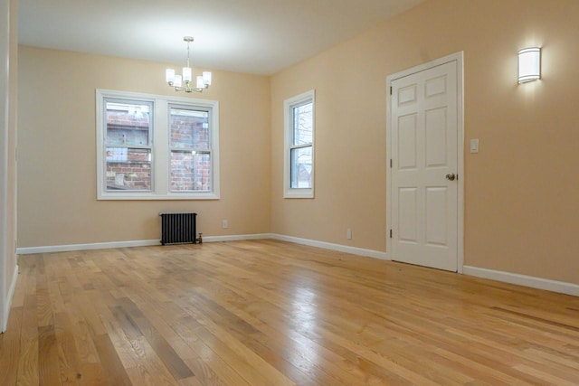 unfurnished dining area featuring baseboards, light wood finished floors, an inviting chandelier, and radiator