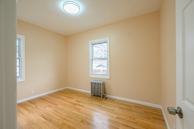 empty room featuring radiator, baseboards, and wood finished floors