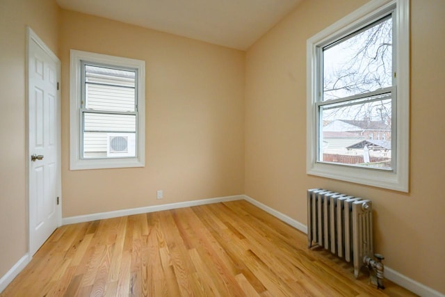 spare room with light wood-style floors, radiator, and baseboards