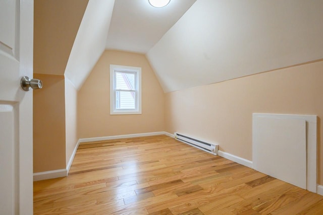 additional living space with lofted ceiling, baseboards, a baseboard heating unit, and wood finished floors