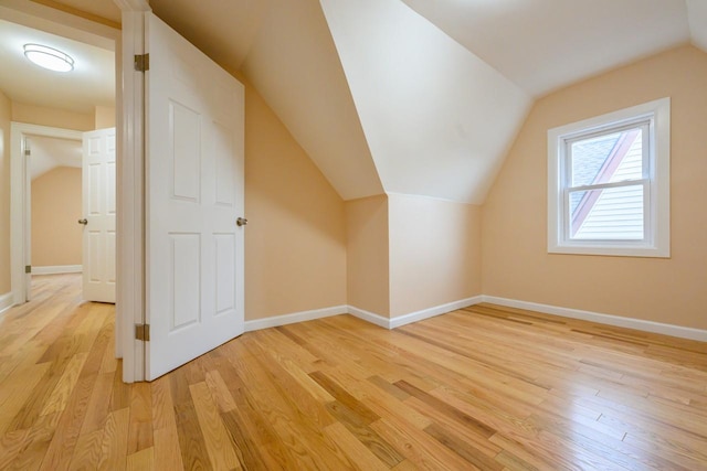 bonus room featuring lofted ceiling, light wood-style flooring, and baseboards