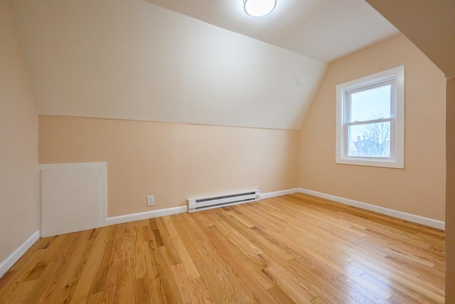 bonus room featuring a baseboard heating unit, light wood-type flooring, lofted ceiling, and baseboards