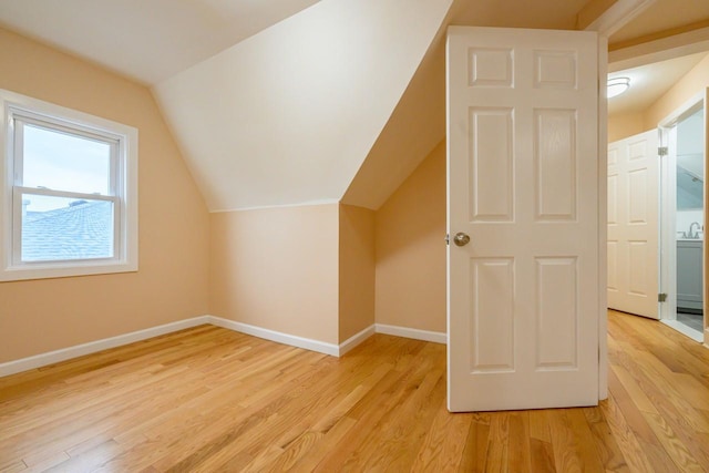 additional living space with lofted ceiling, light wood-style floors, and baseboards